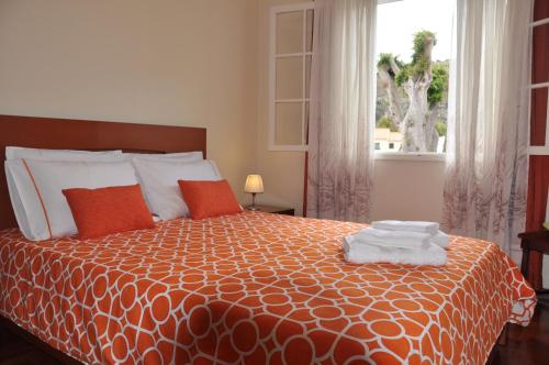 1 dormitorio con cama con colcha de color naranja y ventana en Casas do Largo Dos Milagres, en Machico
