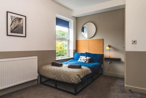 a bedroom with a bed with blue sheets and a window at Stunning Apartment Derby Free Wi-Fi & Parking in Derby