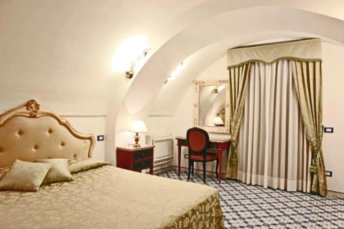a bedroom with a bed and a desk and a mirror at Villa Borgo San Michele in Amalfi