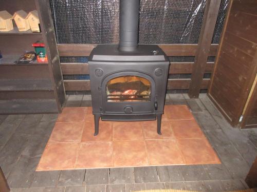 a stove sitting on a tiled floor in a room at DogrunCafe & Resorts JENNIE West-Karuizawa in Miyota