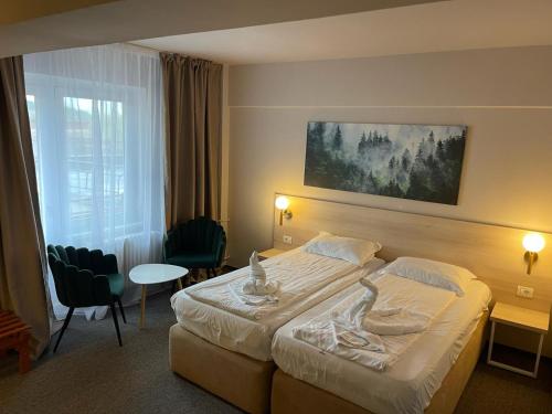 um quarto de hotel com uma cama, uma mesa e cadeiras em Bacolux Santis, Covasna em Covasna