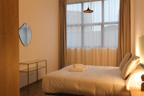 a bedroom with a bed with a window and a mirror at MonKeys Apartments Miraflores in Seville