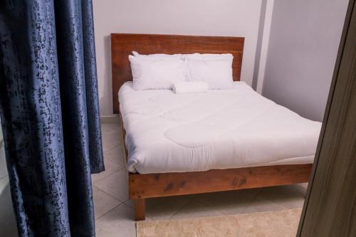 een bed met witte lakens en kussens in een kamer bij Cosy Homes Bomet in Bomet