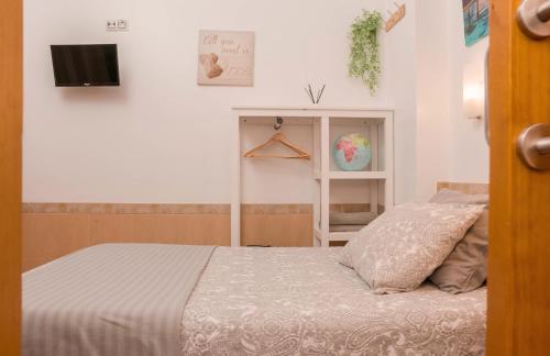1 dormitorio con 1 cama y TV en la pared en ALOJAMIENTO Aire De Los Alcores, en El Viso del Alcor