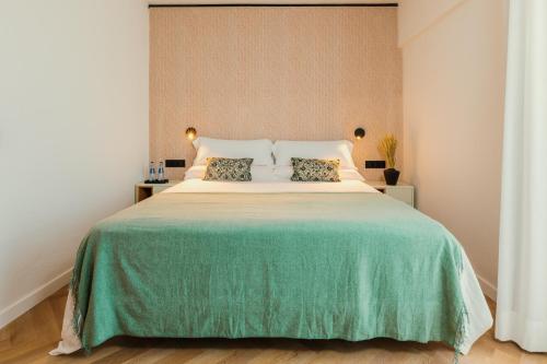 a bedroom with a large bed with a green blanket at Apartamentos Paya in Es Pujols