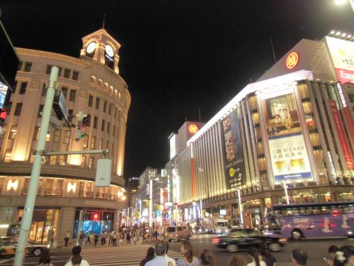 a busy city street at night with a clock tower at Hotel Monterey Ginza in Tokyo