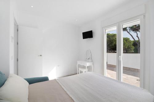 een witte slaapkamer met een bed en een glazen schuifdeur bij Villa moderna en Chiclana in Chiclana de la Frontera