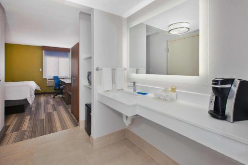 Baño blanco con lavabo y espejo en Holiday Inn Express Fairfax-Arlington Boulevard, an IHG Hotel, en Fairfax