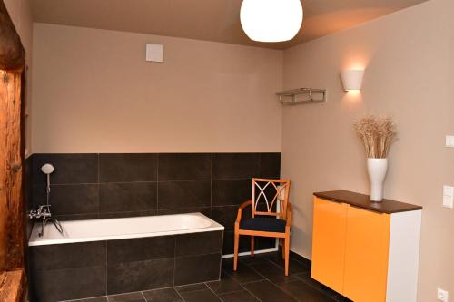 a bathroom with a bath tub and a chair at Domizil Eutschützblick in Bannewitz