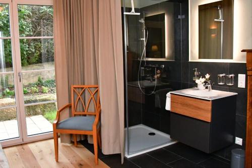uma casa de banho com um lavatório, um chuveiro e uma cadeira. em Domizil Eutschützblick em Bannewitz