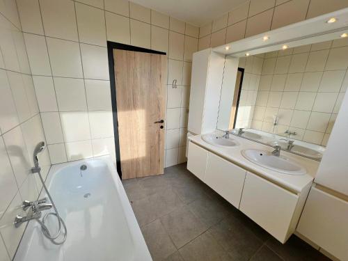 uma casa de banho com 2 lavatórios, uma banheira e um espelho. em Résidence Thier Antoine em Noiseux