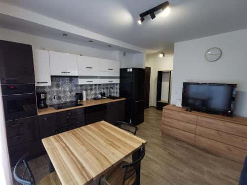a kitchen with a wooden table and a tv at Sunny Apartament in Darłowo