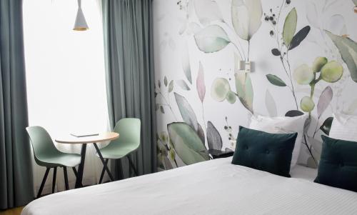 Habitación de hotel con cama, mesa y sillas en Court Garden Hotel - Ecodesigned en The Hague