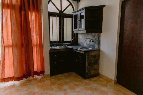 a kitchen with a sink and a window with orange curtains at Romantic garden hotel in Negombo