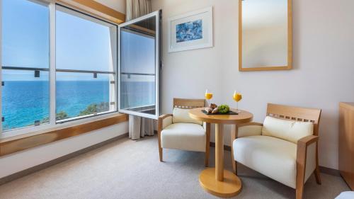 a room with two chairs and a table with two windows at Family Hotel La Luna - All inclusive in Lun