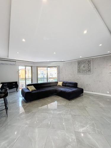 un grand salon avec un canapé noir et un piano dans l'établissement Résidence l'Empire, à Cannes