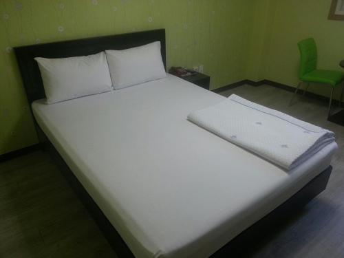 1 cama con sábanas blancas y almohada blanca en Hansol Hotel en Gyeongju