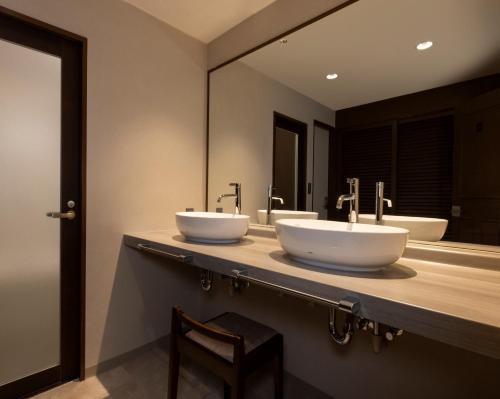 a bathroom with two sinks and a mirror at Kamogawa Grand Hotel in Kamogawa