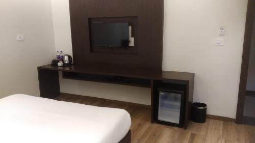 a bedroom with a bed and a tv on a wall at Enrise by Sayaji Rewa in Rewa