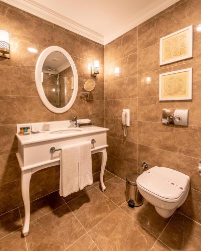 a bathroom with a sink and a toilet and a mirror at Vuni Palace Hotel & Casino & SPA in Kyrenia