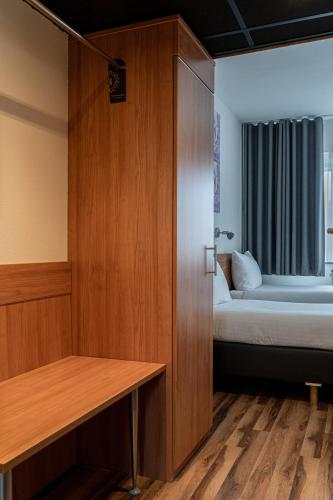 a small room with a bed and a wooden cabinet at Hotel de Duif Lisse - Keukenhof in Lisse