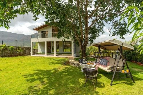 a garden with a swing and an umbrella and a house at EKOSTAY - Amani Villa in Khopoli