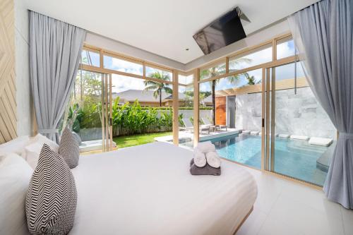 um quarto com uma cama grande e uma piscina em Himmapana Villas - SHA Extra Plus em Kamala Beach