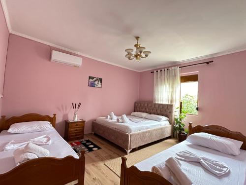2 Betten in einem Zimmer mit rosa Wänden in der Unterkunft Vjosa Guest House in Memaliaj