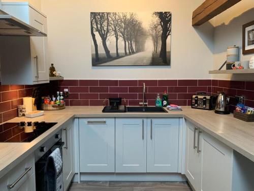 a kitchen with white cabinets and a painting on the wall at Studio 3B The Carriage House York 6m Village Location in York