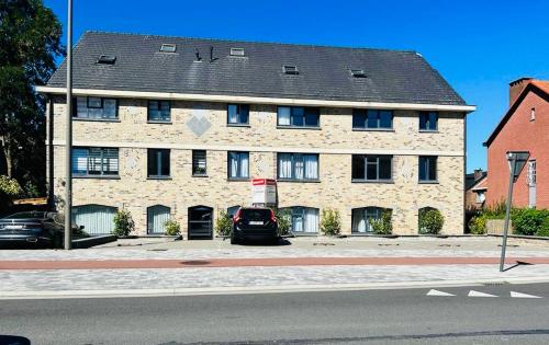 a large brick building with a car parked in front of it at Appart Brussels EXPO & ATOMIUM in Grimbergen