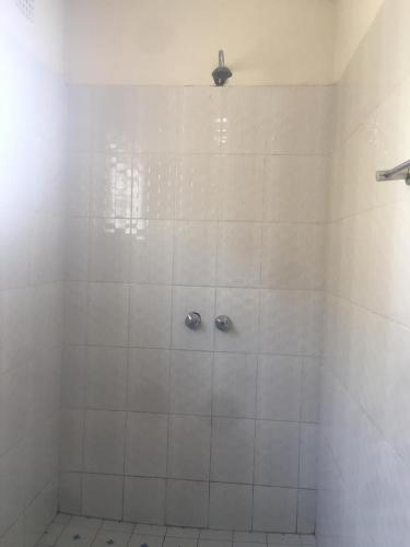a white tiled shower with two faucets in a bathroom at Villa Ntowe Lodge in Blantyre