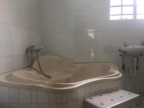 a bath tub in a bathroom with a sink at Villa Ntowe Lodge in Blantyre