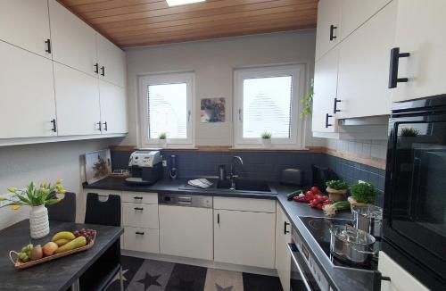 a kitchen with white cabinets and black counter tops at Ferienhaus am Stadtgraben in Hornbach