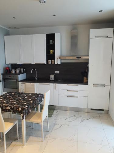 uma cozinha com armários brancos e uma mesa e cadeiras em MARCO'S HOUSE em Sanremo