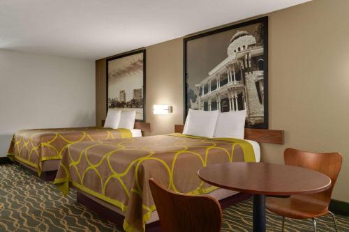a hotel room with two beds and a table at Super 8 by Wyndham Pearl/Jackson/East in Pearl