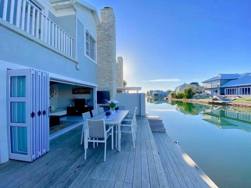 a deck with a table and chairs next to a body of water at Canal 04 in Jeffreys Bay