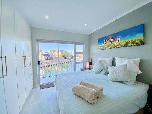 a bedroom with a large white bed with a balcony at Canal 04 in Jeffreys Bay
