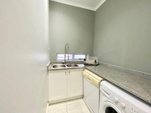 a kitchen with a sink and a washing machine at Canal 04 in Jeffreys Bay