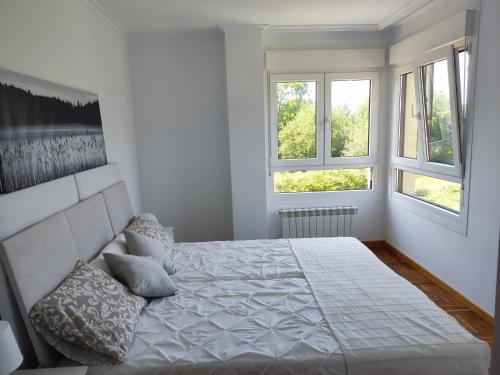 1 dormitorio blanco con 1 cama y 2 ventanas en Apartamento MAR y MONTAÑA ASTURIAS, en Posada de Llanes