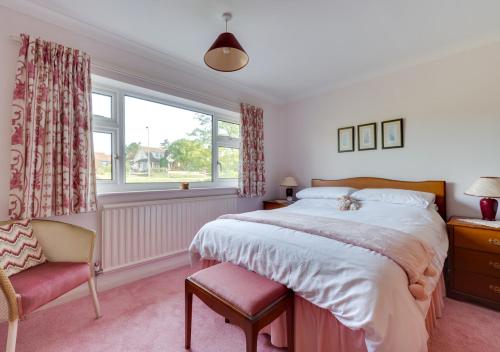 a bedroom with a bed and a chair and a window at Willow House in Halesworth