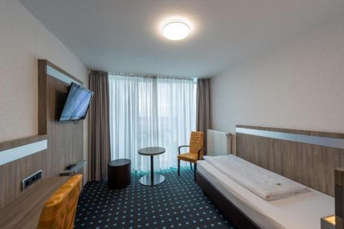 a hotel room with a bed and a table and a television at PANORAMA HOTEL in Neustadt an der Weinstraße in Neustadt an der Weinstraße