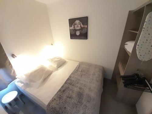 - une petite chambre avec un lit et une photo sur le mur dans l'établissement Appartement Village Naturiste Mystere, au Cap d'Agde