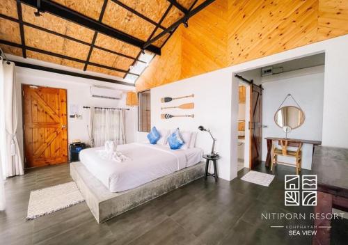1 dormitorio con 1 cama blanca grande con almohadas azules en Nitiporn Resort kohphayam & seaagain bar and restaurants, en Ko Phayam
