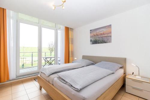 ein Schlafzimmer mit einem Bett und einem großen Fenster in der Unterkunft Nordseeblick 5 in Cuxhaven