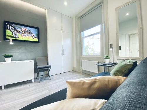 a living room with a couch and a tv on the wall at Apt 03 Beachside Beauty Central Studio Steps from Cafes in Brighton & Hove