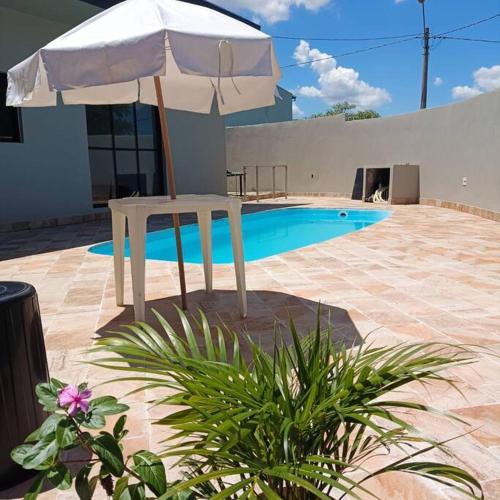 a white umbrella sitting next to a swimming pool at Recanto Shalom 3 dormitórios in São Carlos