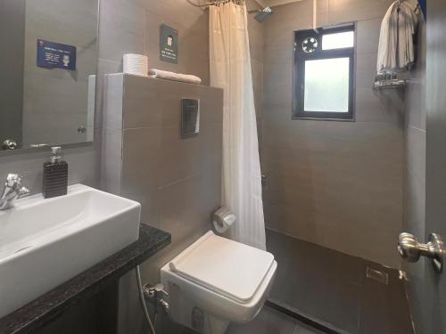 a bathroom with a sink and a toilet and a window at Backpacker Cowies in Mumbai