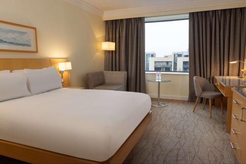 a hotel room with a bed and a desk and a window at Hilton Dublin Airport in Cloghran