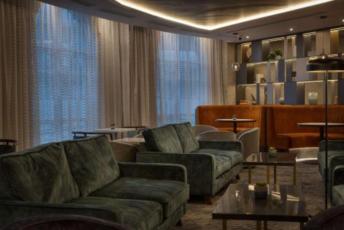 a living room with couches and tables and windows at Hilton Cardiff in Cardiff