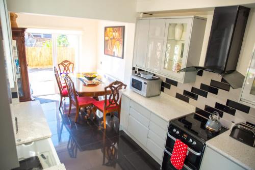 uma cozinha com uma mesa e um fogão em Rare London 6bedroom House em South Norwood